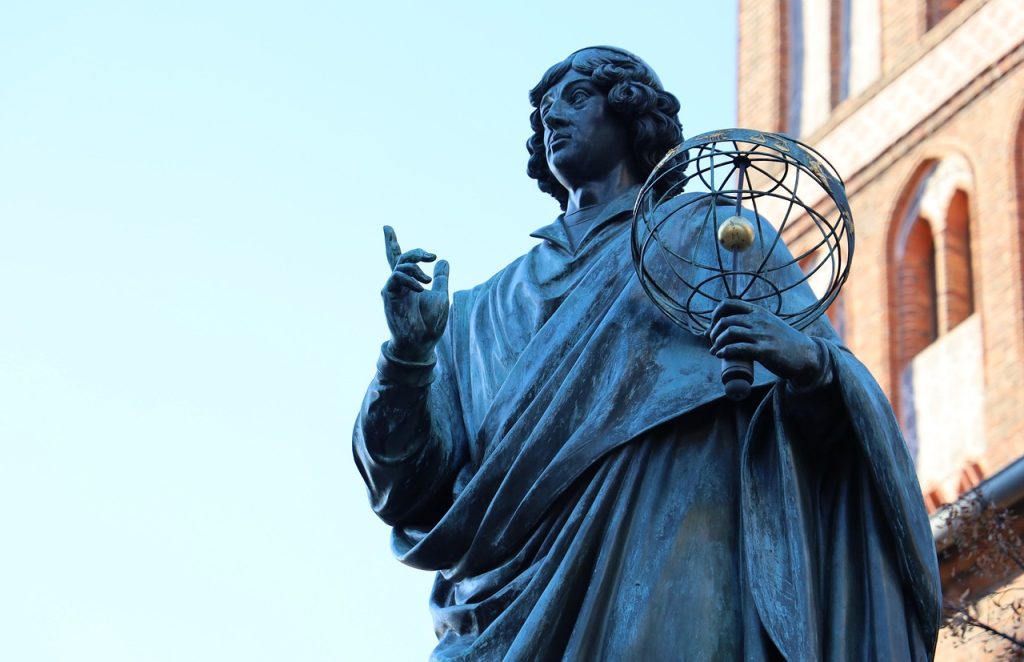 Mikołaj Kopernik trzyma w ręce makietę wszechświata